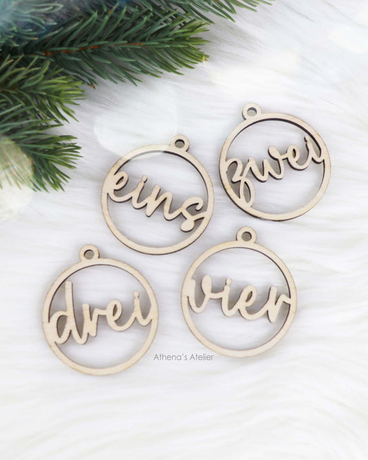 Set aus vier runden Adventszahlen aus hellem Holz, mit den Wörtern eins, zwei, drei, vier in eleganter Schreibschrift lasergeschnitten.