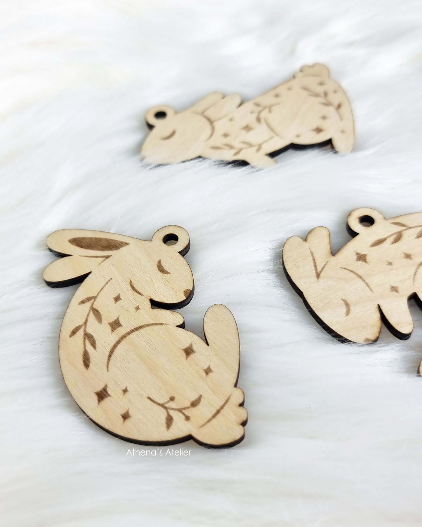 Set aus drei handgefertigten Holz-Anhängern in Hasenform mit filigraner Gravur von Zweigen und Sternen für die Osterdekoration – Athena's Atelier.