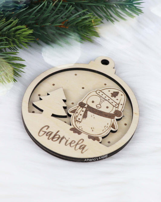 Runder Weihnachtsbaum-Anhänger aus Holz, personalisiert mit einem Pinguin und Wunschnamen.
