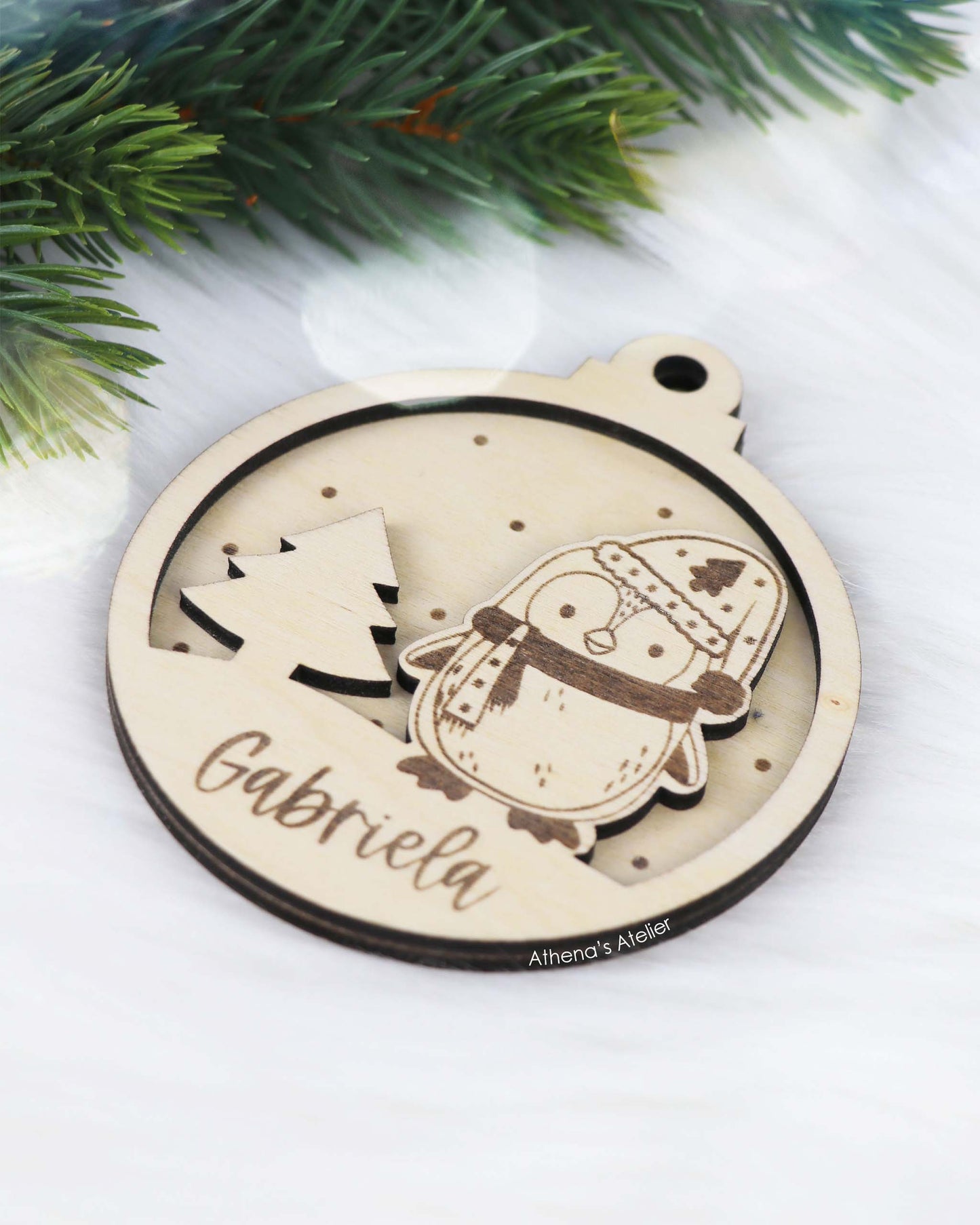 Runder Weihnachtsbaum-Anhänger aus Holz, personalisiert mit einem Pinguin und Wunschnamen.