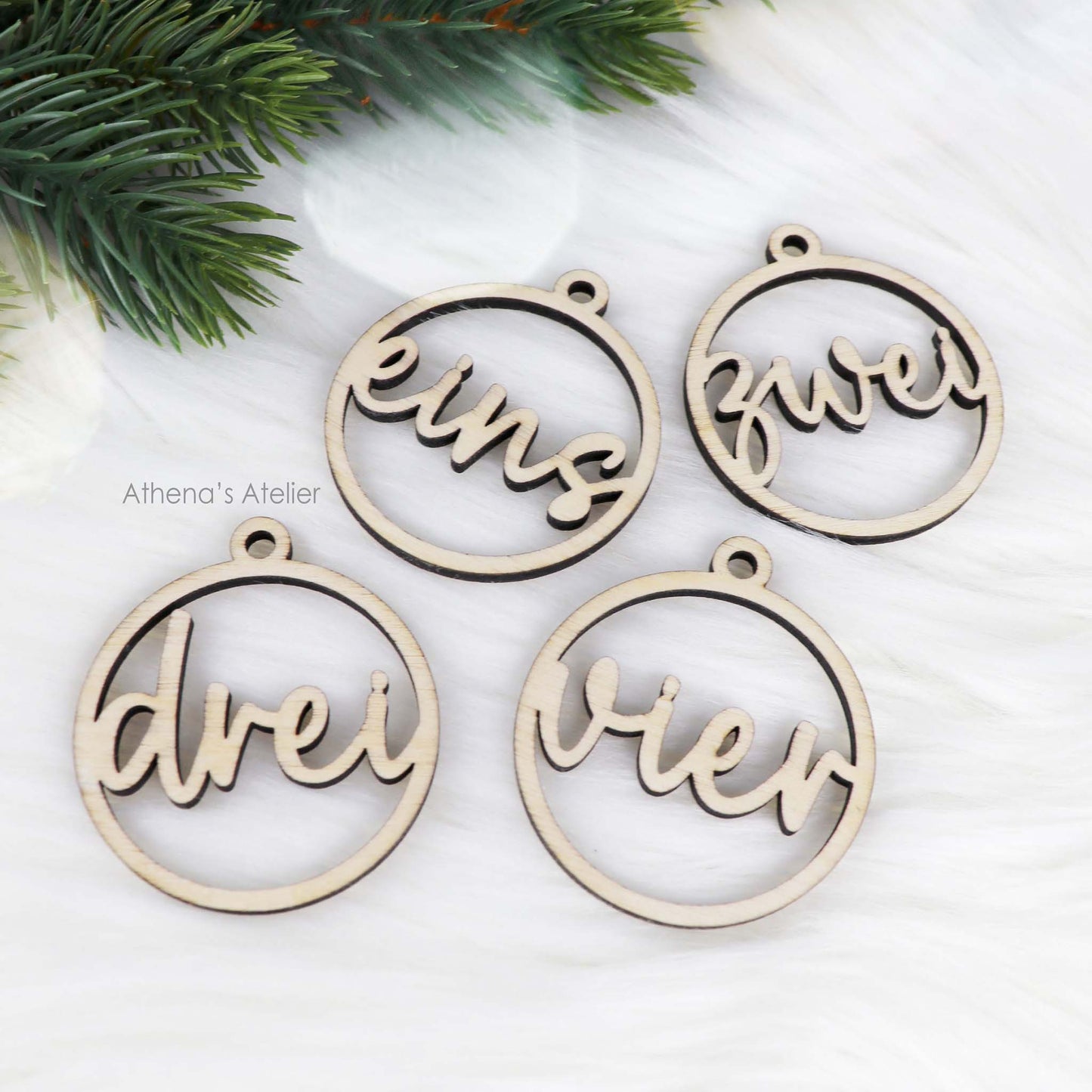 Set aus vier runden Adventszahlen aus hellem Holz, mit den Wörtern eins, zwei, drei, vier in eleganter Schreibschrift lasergeschnitten.