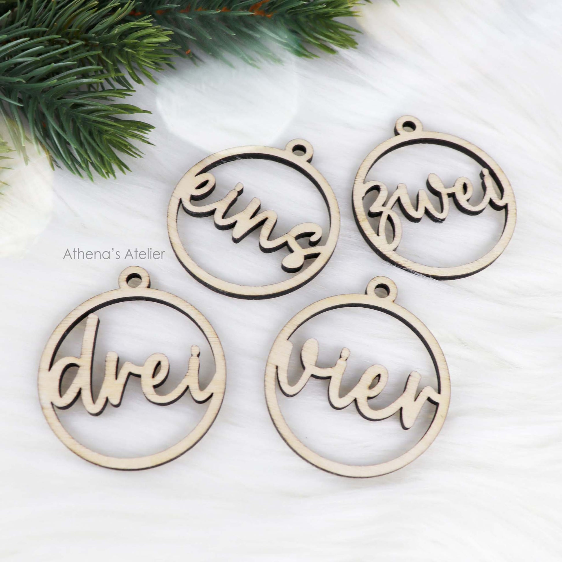 Set aus vier runden Adventszahlen aus hellem Holz, mit den Wörtern eins, zwei, drei, vier in eleganter Schreibschrift lasergeschnitten.