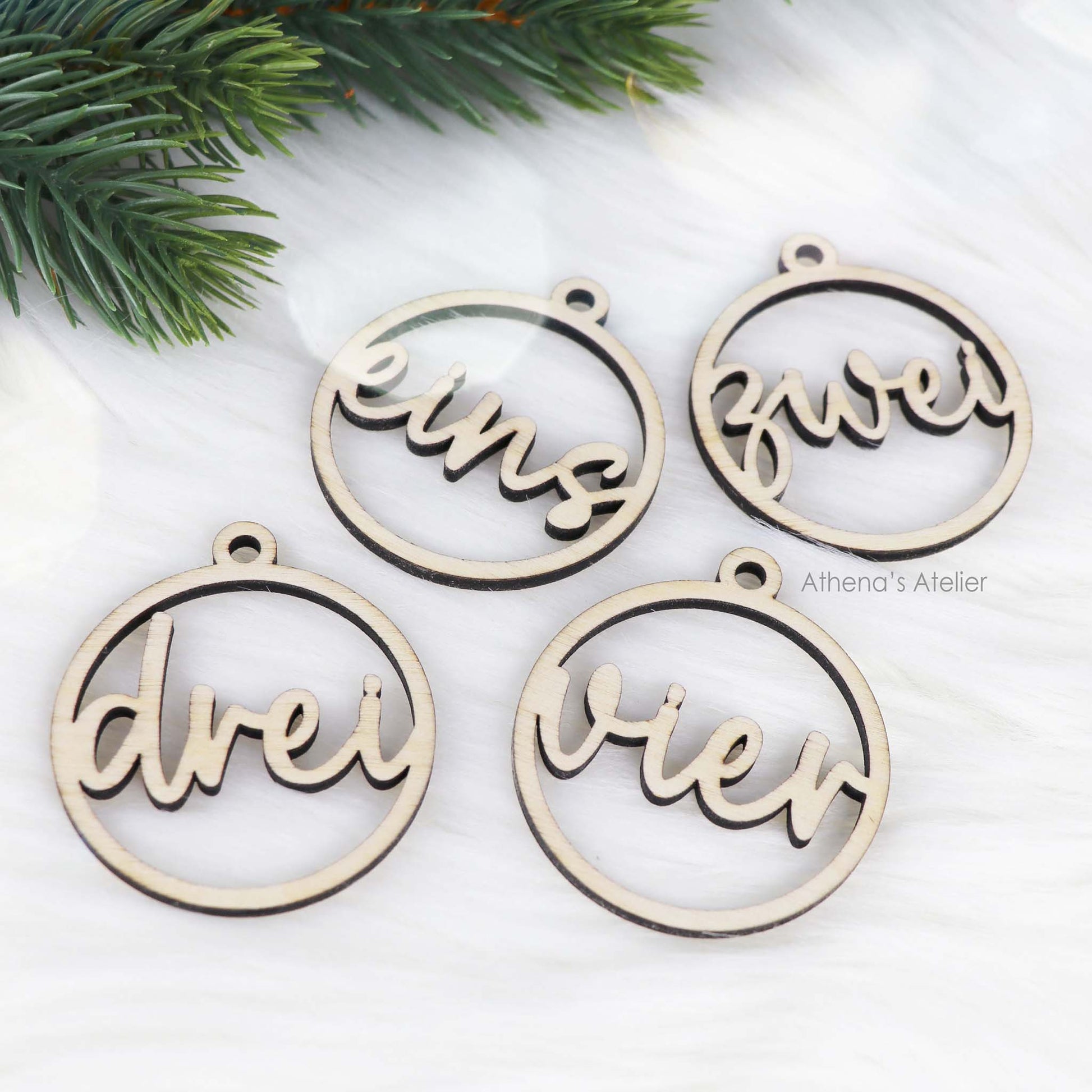 Set aus vier runden Adventszahlen aus hellem Holz, mit den Wörtern eins, zwei, drei, vier in eleganter Schreibschrift lasergeschnitten.