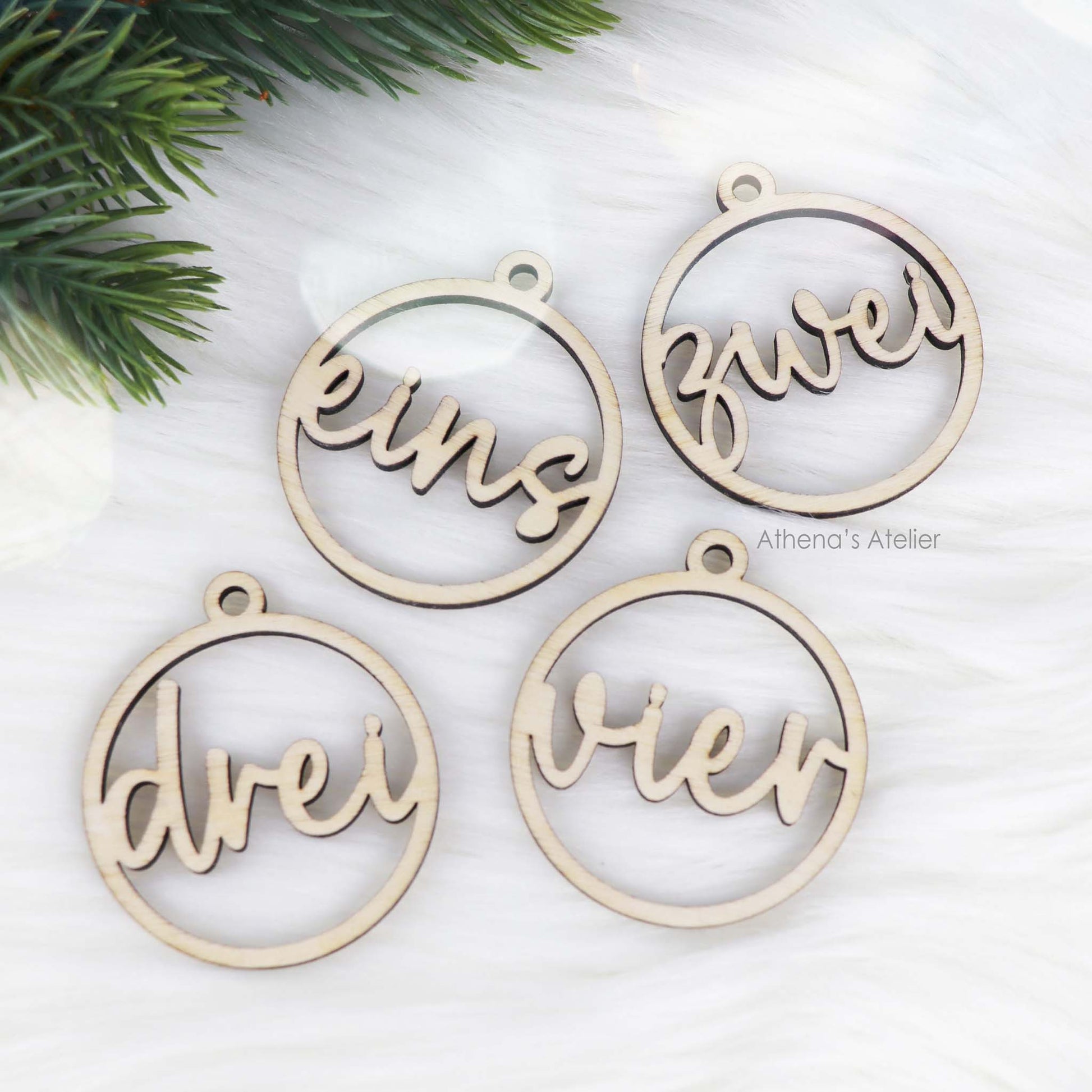 Set aus vier runden Adventszahlen aus hellem Holz, mit den Wörtern eins, zwei, drei, vier in eleganter Schreibschrift lasergeschnitten.