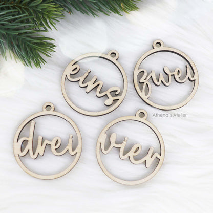 Set aus vier runden Adventszahlen aus hellem Holz, mit den Wörtern eins, zwei, drei, vier in eleganter Schreibschrift lasergeschnitten.