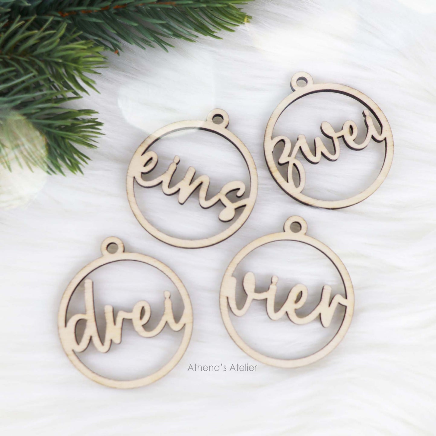 Set aus vier runden Adventszahlen aus hellem Holz, mit den Wörtern eins, zwei, drei, vier in eleganter Schreibschrift lasergeschnitten.