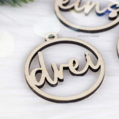 Set aus vier runden Adventszahlen aus hellem Holz, mit den Wörtern eins, zwei, drei, vier in eleganter Schreibschrift lasergeschnitten.