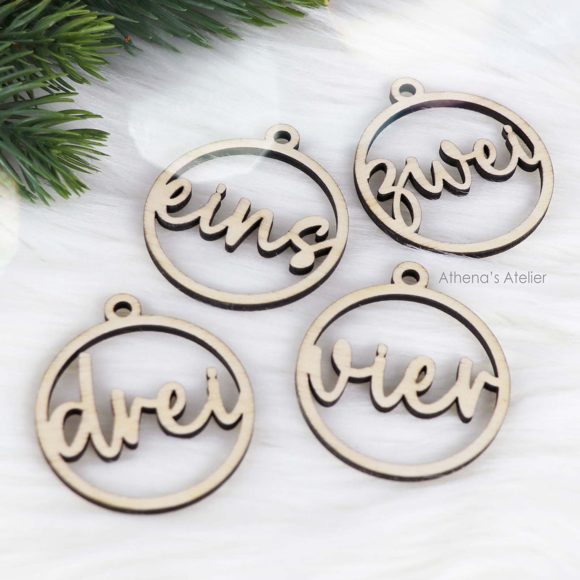 Set aus vier runden Adventszahlen aus hellem Holz, mit den Wörtern eins, zwei, drei, vier in eleganter Schreibschrift lasergeschnitten.