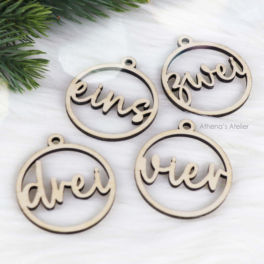 Set aus vier runden Adventszahlen aus hellem Holz, mit den Wörtern eins, zwei, drei, vier in eleganter Schreibschrift lasergeschnitten.