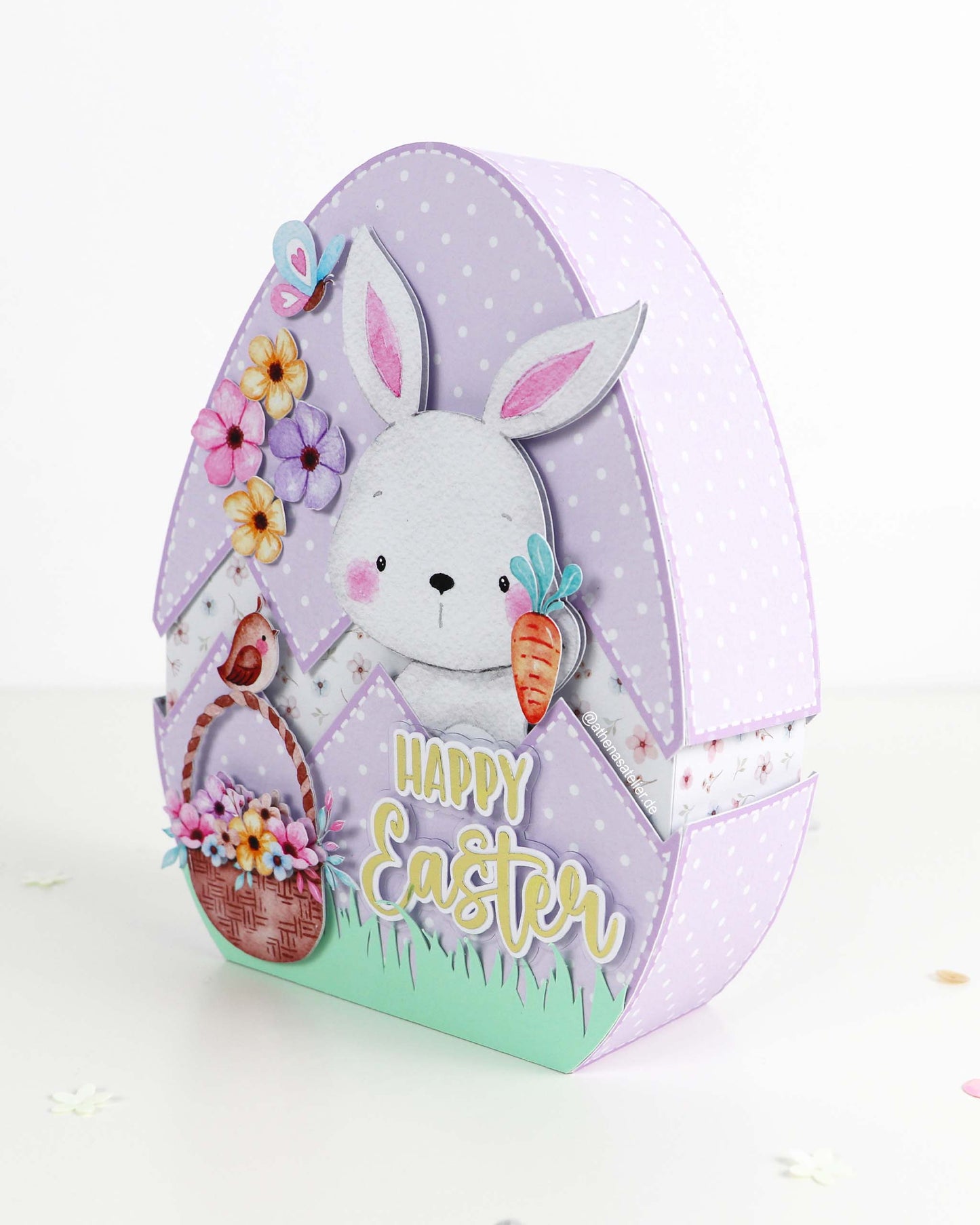 Handgefertigte Oster-Geschenkbox in Eiform aus hochwertigem Motivkarton mit Hasen-Motiv und Aufschrift Frohe Ostern – Athena's Atelier.