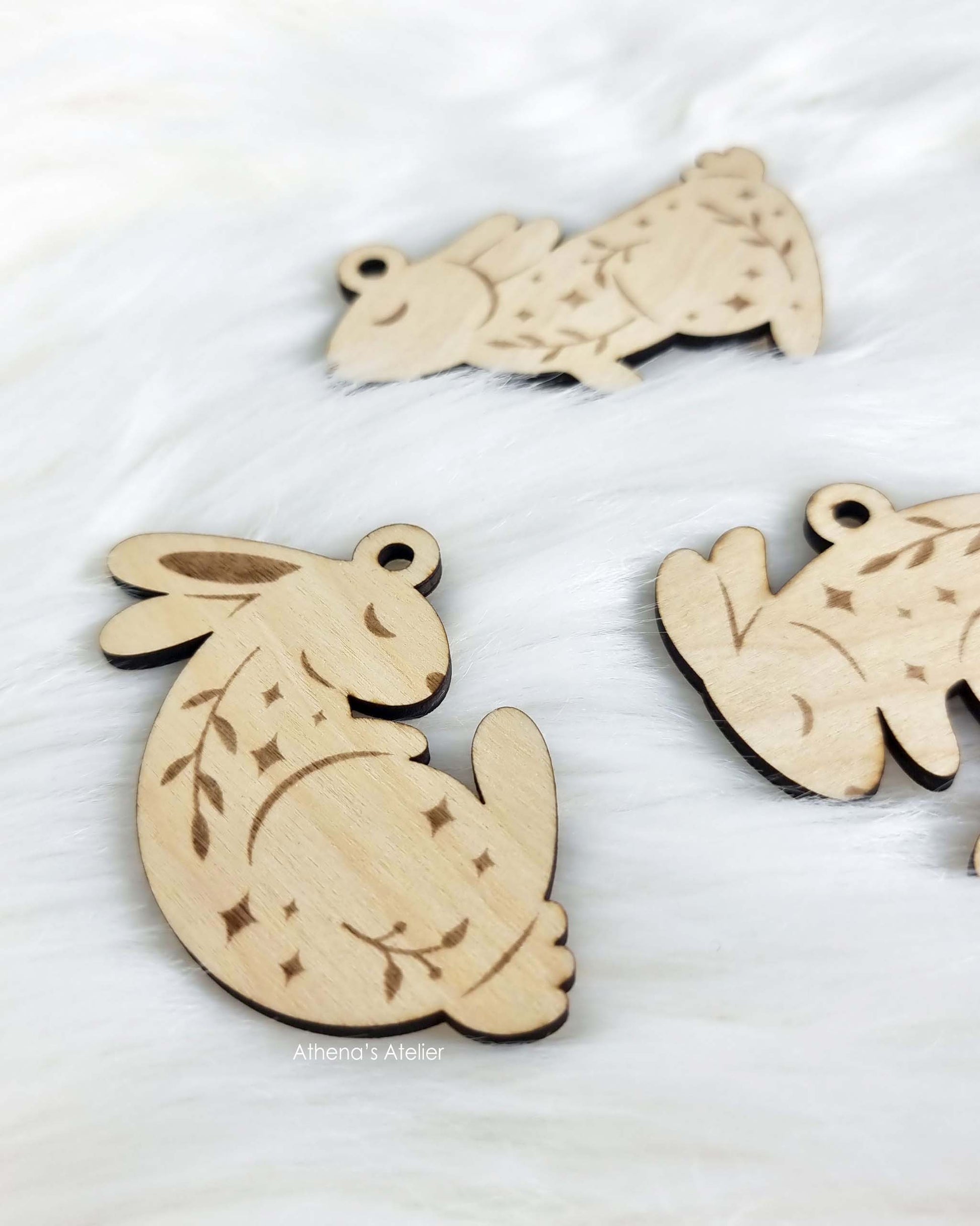 Set aus drei handgefertigten Holz-Anhängern in Hasenform mit filigraner Gravur von Zweigen und Sternen für die Osterdekoration – Athena's Atelier.