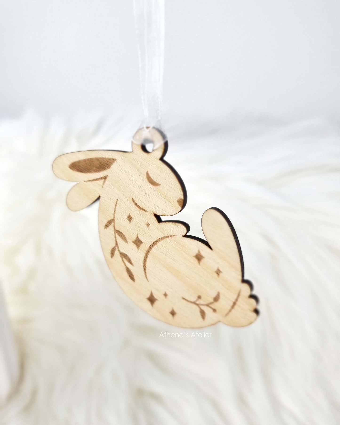 Drei schlafende Osterhasen-Anhänger aus Holz, dekorativ hängend an einem Palmkätzchen-Zweig als traditioneller Osterstrauß – Athena's Atelier.