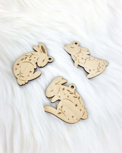 Set aus drei handgefertigten Holz-Anhängern in Hasenform mit filigraner Gravur von Zweigen und Sternen für die Osterdekoration – Athena's Atelier.