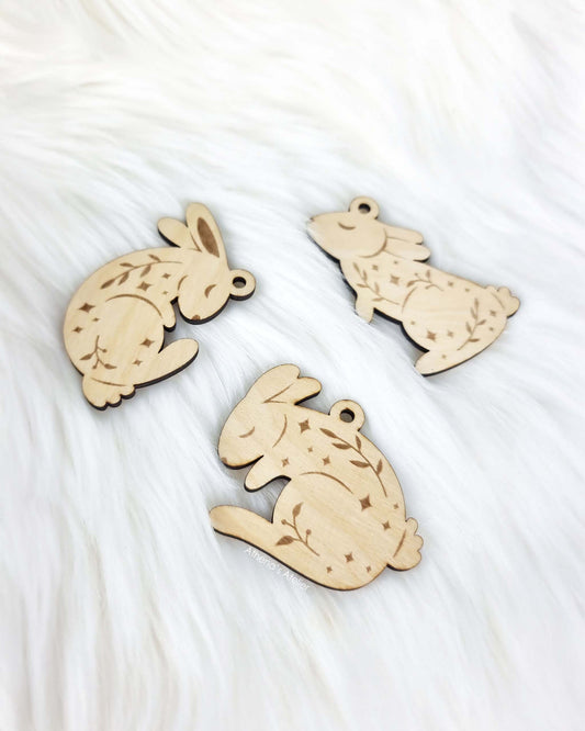 Set aus drei handgefertigten Holz-Anhängern in Hasenform mit filigraner Gravur von Zweigen und Sternen für die Osterdekoration – Athena's Atelier.
