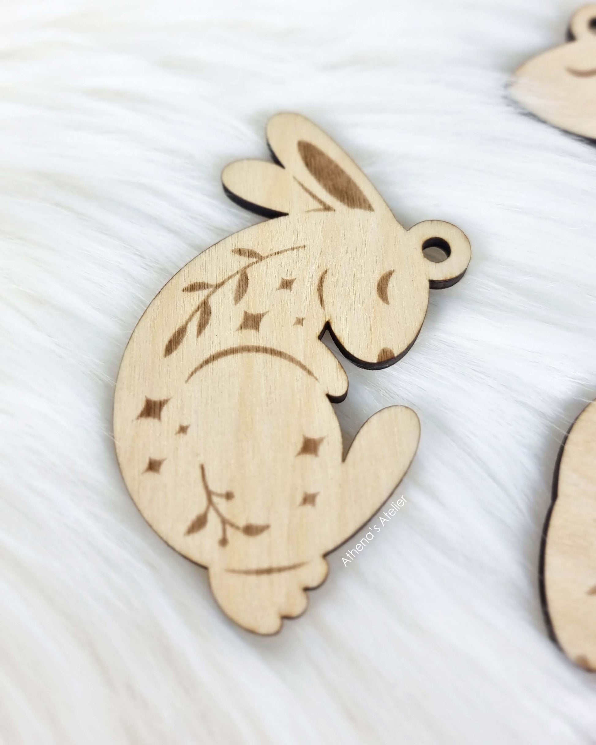 Set aus drei handgefertigten Holz-Anhängern in Hasenform mit filigraner Gravur von Zweigen und Sternen für die Osterdekoration – Athena's Atelier.