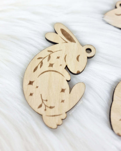 Set aus drei handgefertigten Holz-Anhängern in Hasenform mit filigraner Gravur von Zweigen und Sternen für die Osterdekoration – Athena's Atelier.