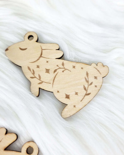 Set aus drei handgefertigten Holz-Anhängern in Hasenform mit filigraner Gravur von Zweigen und Sternen für die Osterdekoration – Athena's Atelier.