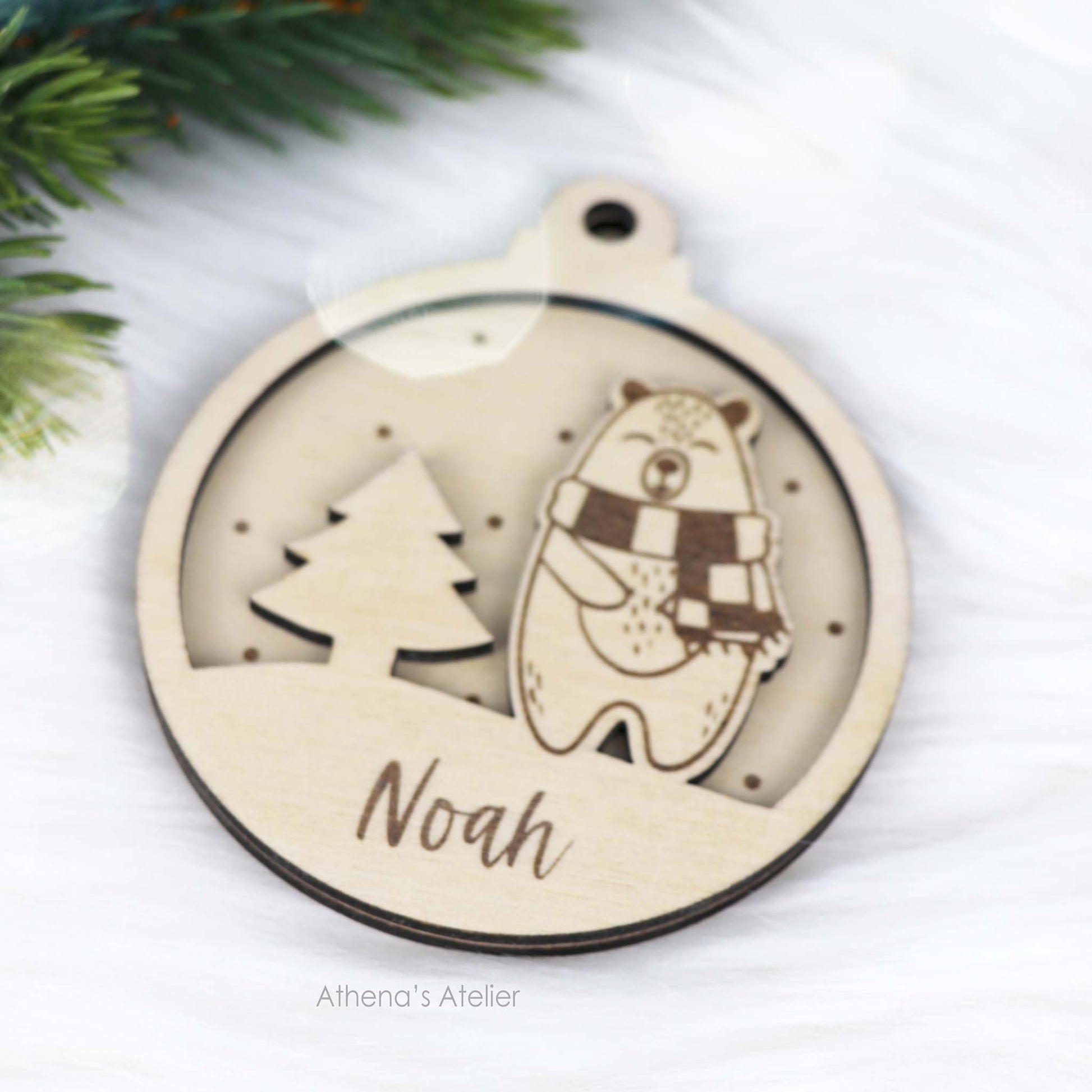 Runder Weihnachtsbaum-Anhänger aus Holz, personalisiert mit einem Bärchen und Wunschnamen.