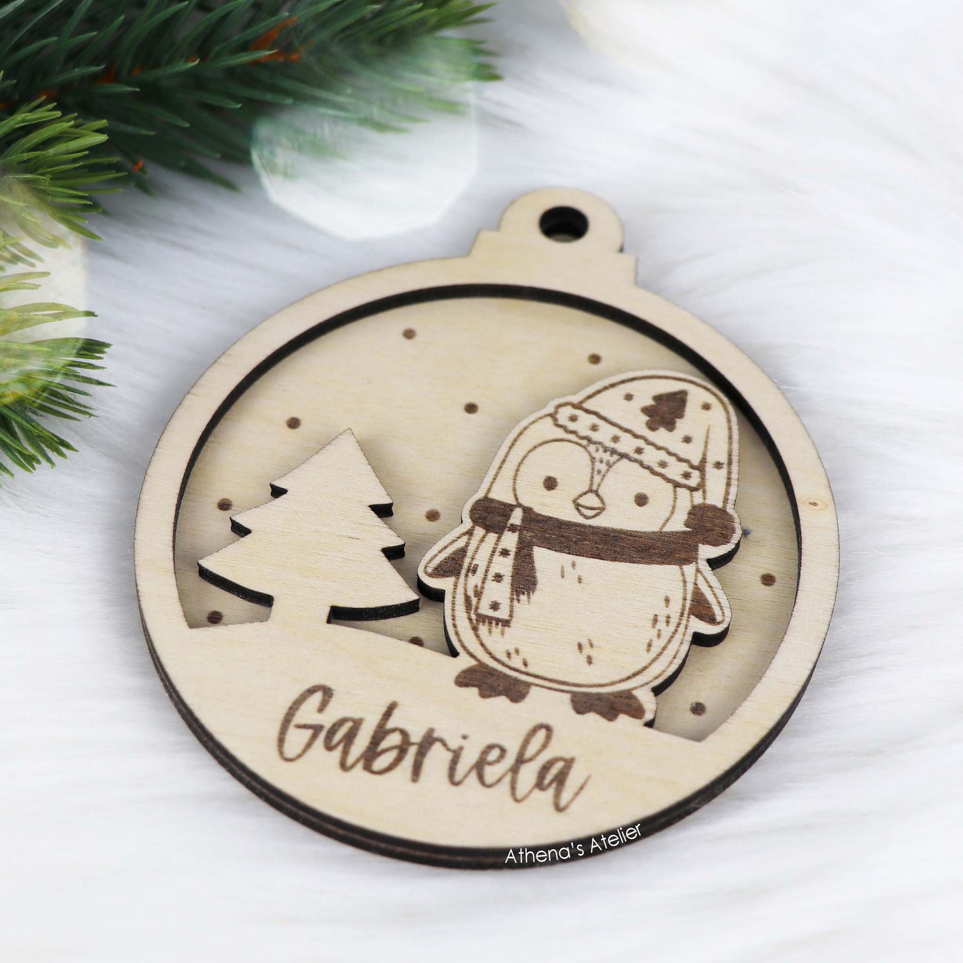 Runder Weihnachtsbaum-Anhänger aus Holz, personalisiert mit einem Pinguin und Wunschnamen.