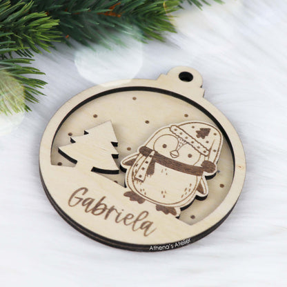 Runder Weihnachtsbaum-Anhänger aus Holz, personalisiert mit einem Pinguin und Wunschnamen.