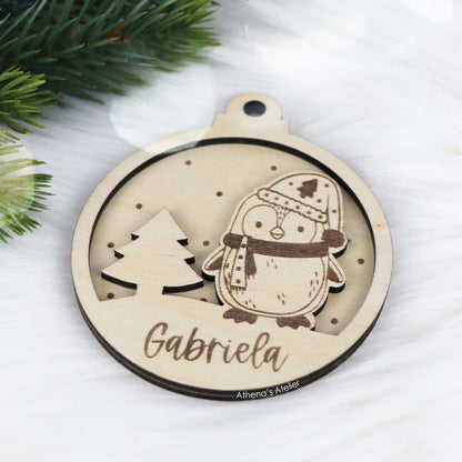 Runder Weihnachtsbaum-Anhänger aus Holz, personalisiert mit einem Pinguin und Wunschnamen.