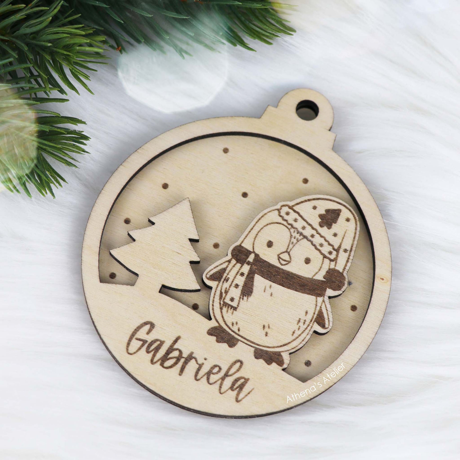 Runder Weihnachtsbaum-Anhänger aus Holz, personalisiert mit einem Pinguin und Wunschnamen.