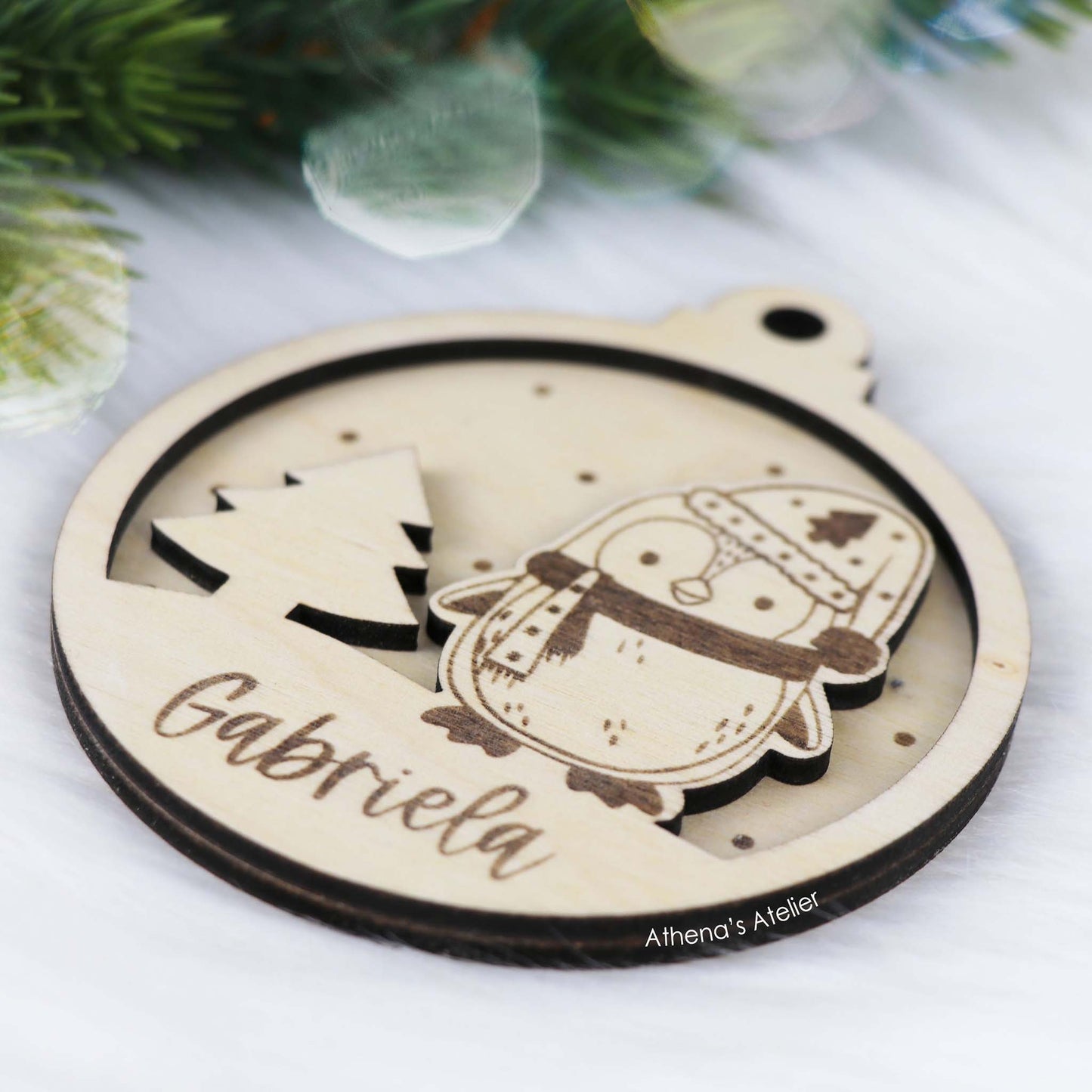 Runder Weihnachtsbaum-Anhänger aus Holz, personalisiert mit einem Pinguin und Wunschnamen.