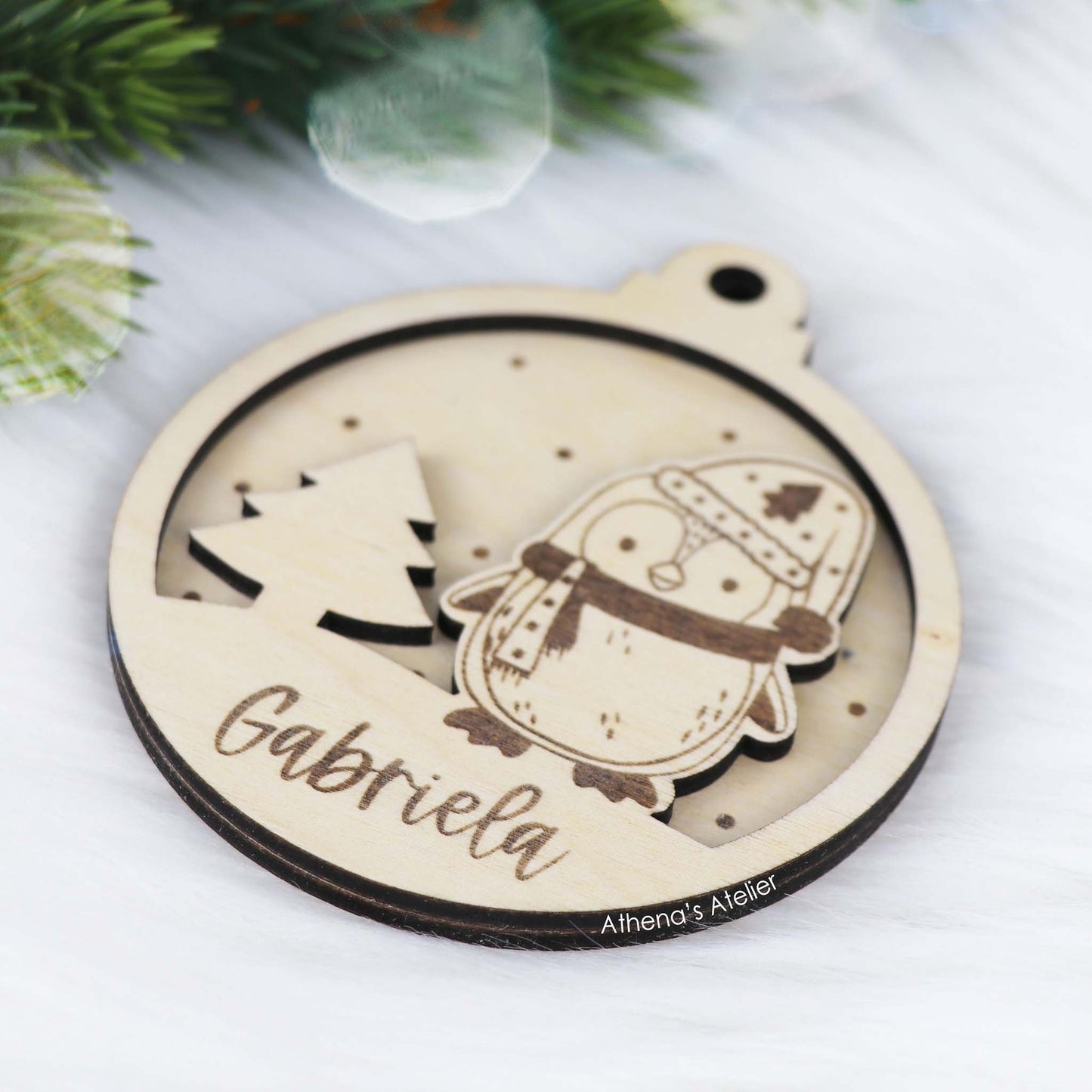 Runder Weihnachtsbaum-Anhänger aus Holz, personalisiert mit einem Pinguin und Wunschnamen.