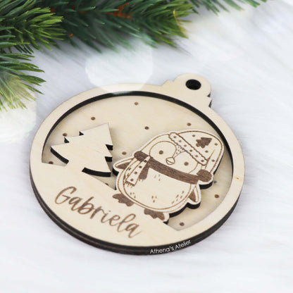 Runder Weihnachtsbaum-Anhänger aus Holz, personalisiert mit einem Pinguin und Wunschnamen.
