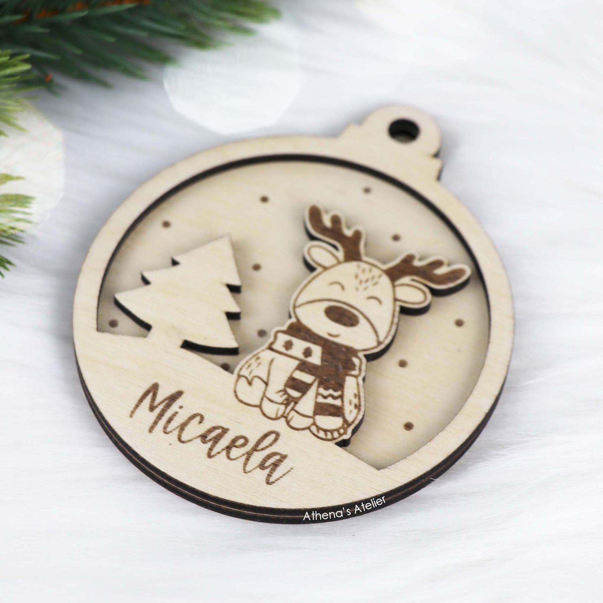 Runder Weihnachtsbaum-Anhänger aus Holz, personalisiert mit einem Rentier und Wunschnamen.
