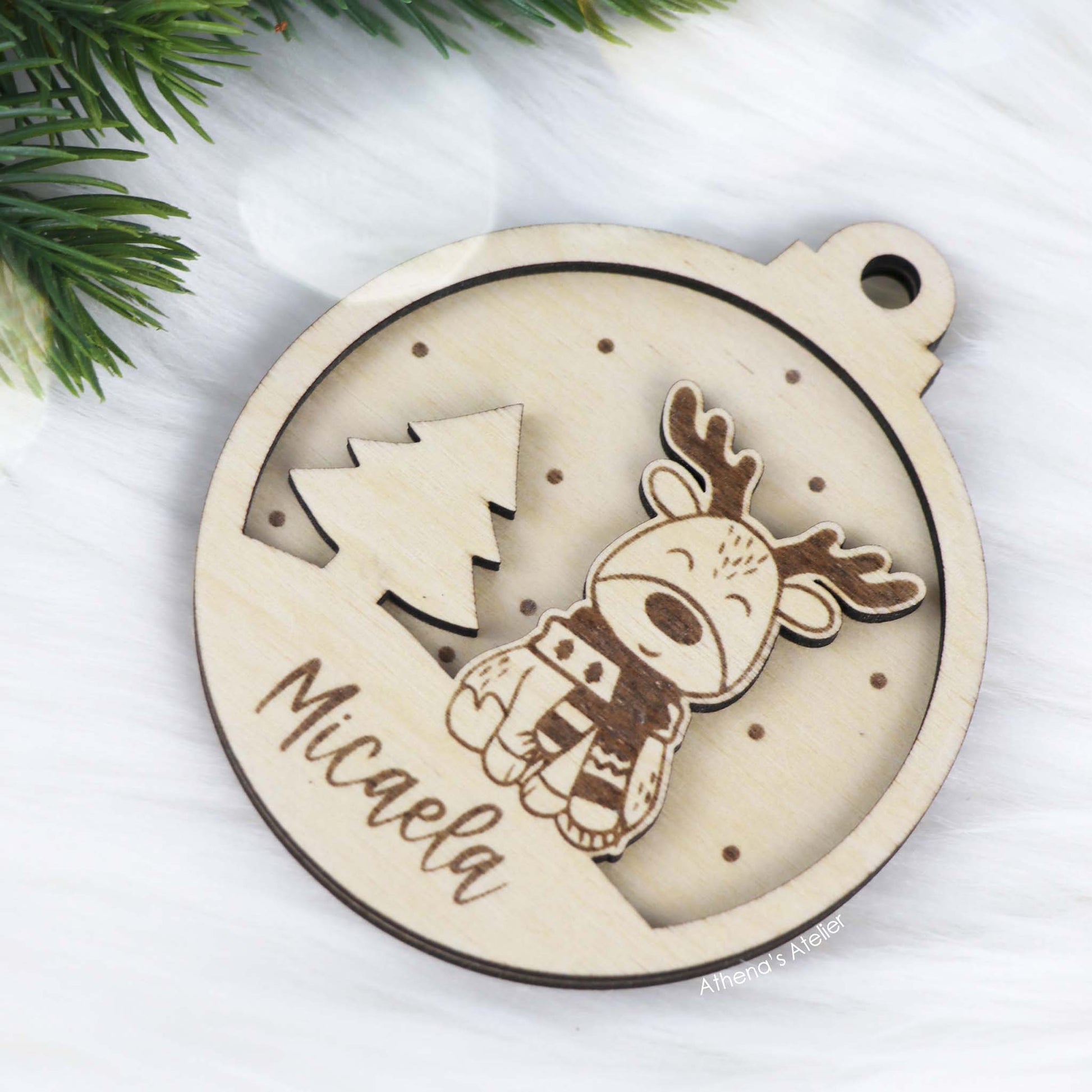 Runder Weihnachtsbaum-Anhänger aus Holz, personalisiert mit einem Rentier und Wunschnamen.