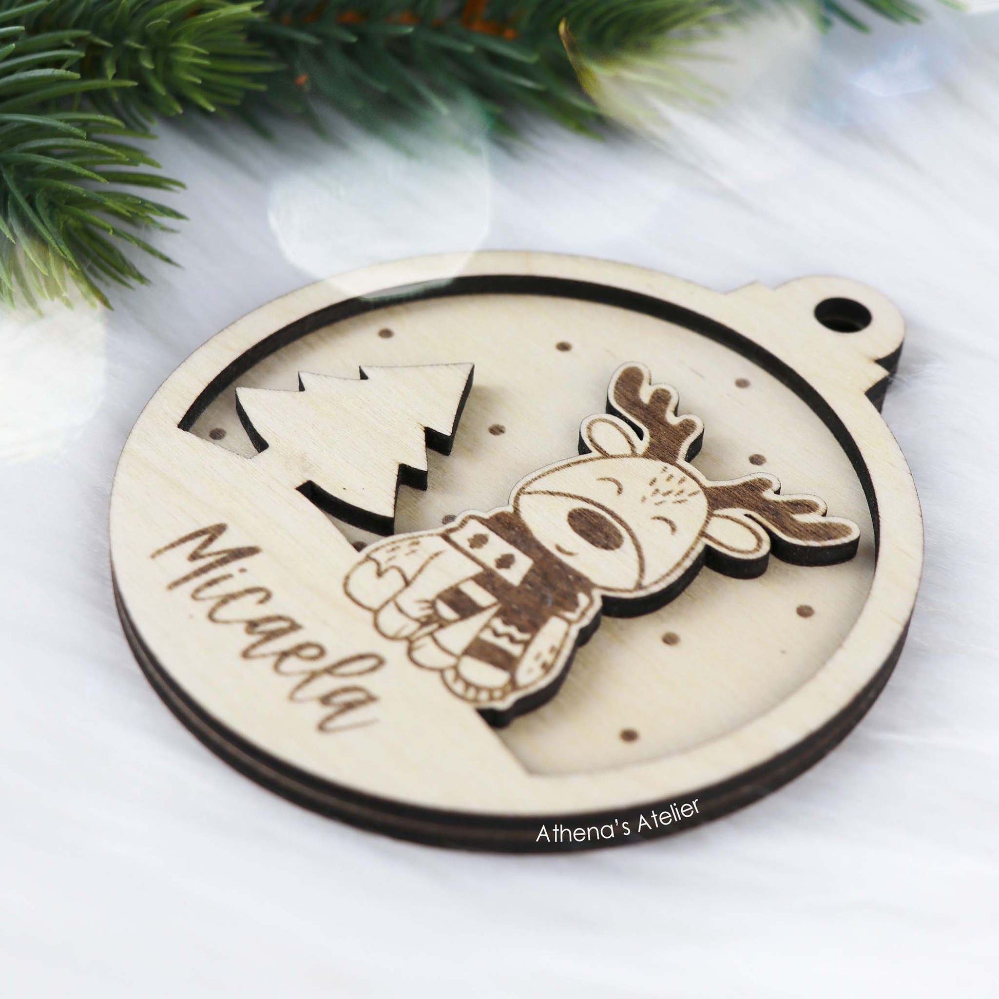 Runder Weihnachtsbaum-Anhänger aus Holz, personalisiert mit einem Rentier und Wunschnamen.