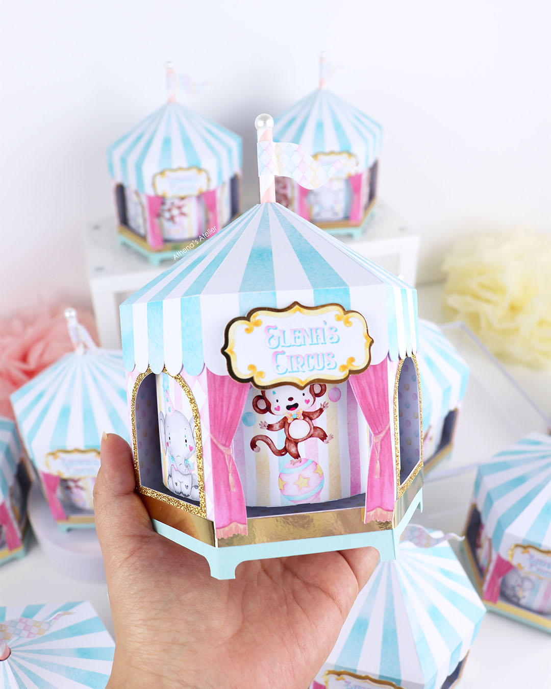 Hand-held view of a spinning circus centerpiece with gold glitter trim and custom name "Elena's Circus" by Athenas Atelier.