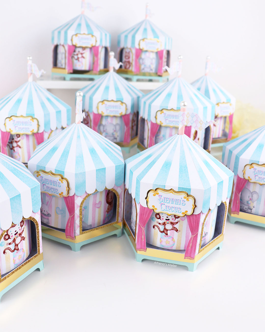 Personalized circus tent carousel spinning centerpiece in light blue and pink with hand-drawn animal illustrations by Athenas Atelier.