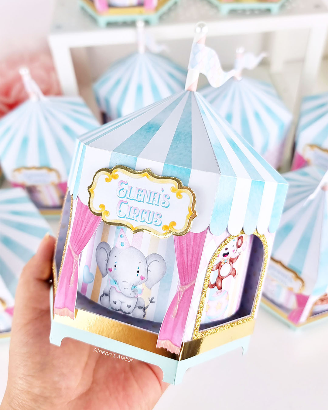 Hand-held view of a spinning circus centerpiece with gold glitter trim and custom name "Elena's Circus" by Athenas Atelier.