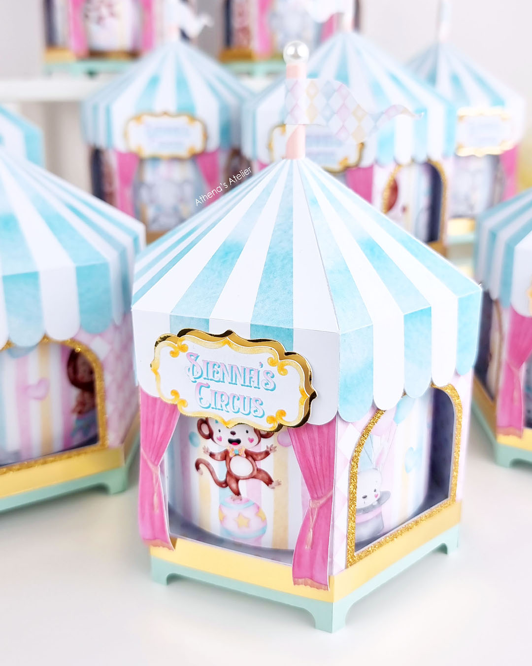 Personalized circus tent carousel spinning centerpiece in light blue and pink with hand-drawn animal illustrations by Athenas Atelier.