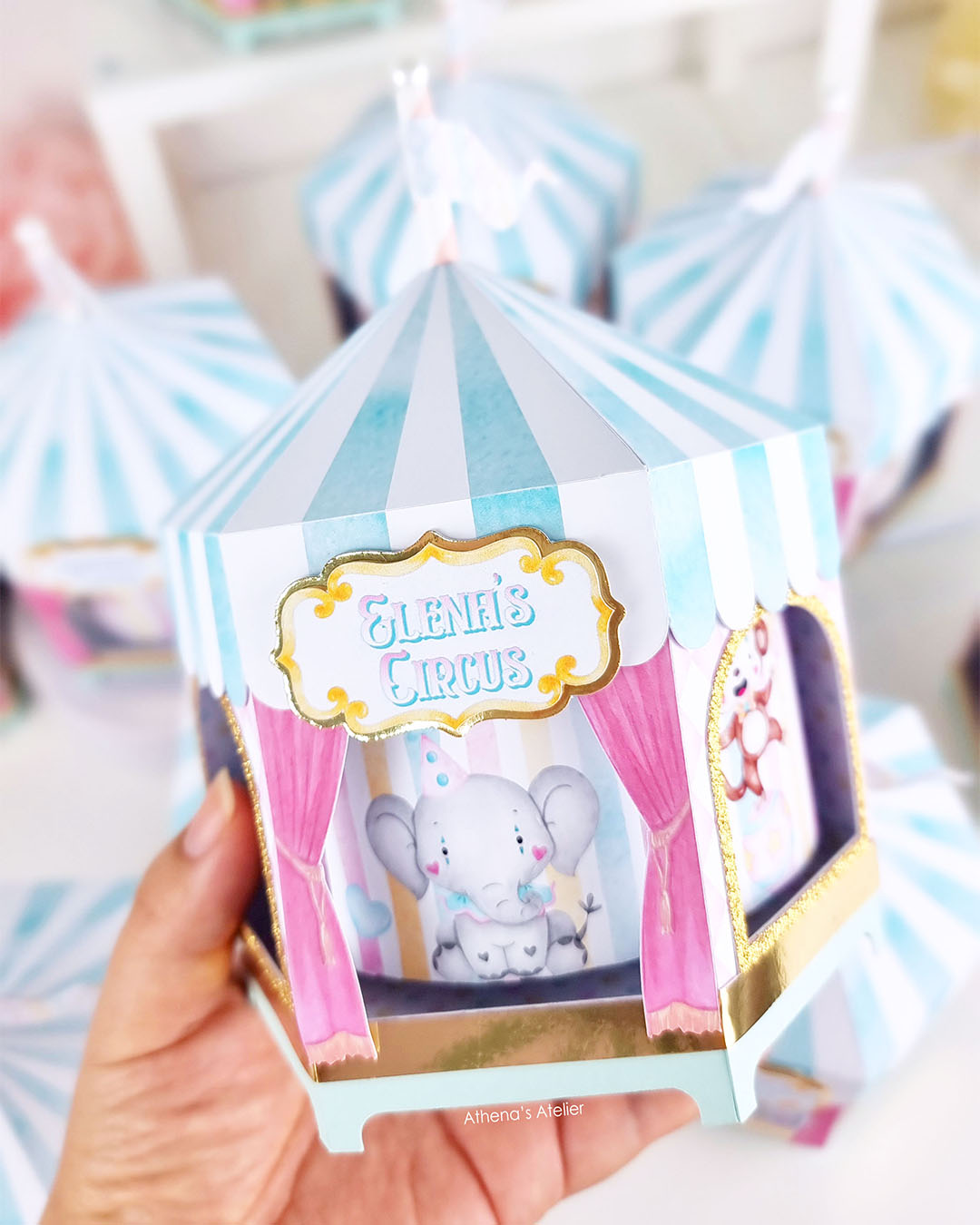 Hand-held view of a spinning circus centerpiece with gold glitter trim and custom name "Elena's Circus" by Athenas Atelier.